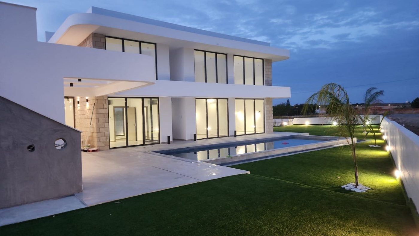 A completed Esser villa at dusk, the pool and garden lighting on